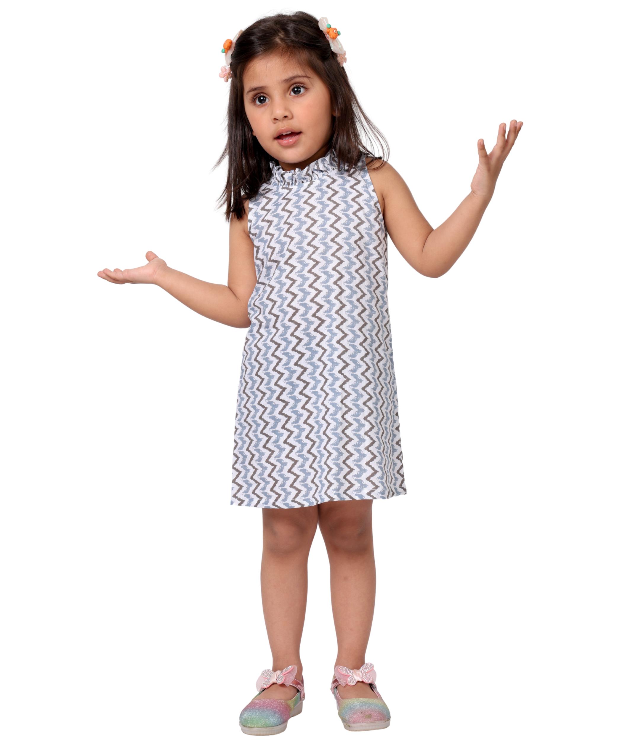 Baby girl wearing Tiny Bunnies white chevron print sleeveless A-line knee length cotton dress with frill neckline